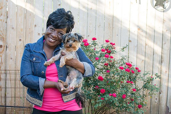 Carla, a breast cancer surviver and ARC patient, holding her dog in a backyard of a house