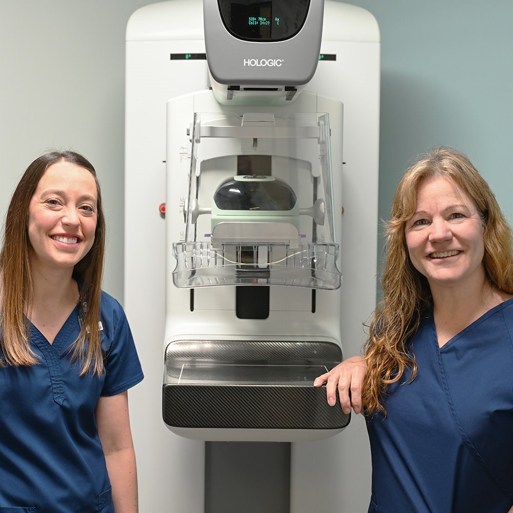 Two ARC mammography technicians next to a mammography machine at ARC
