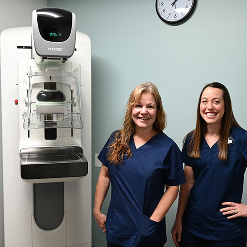Two ARC mammography technicians next to a mammography machine at ARC